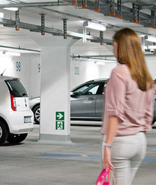 Woman walks to car in bright indoor green parking garage. - lighting for retail