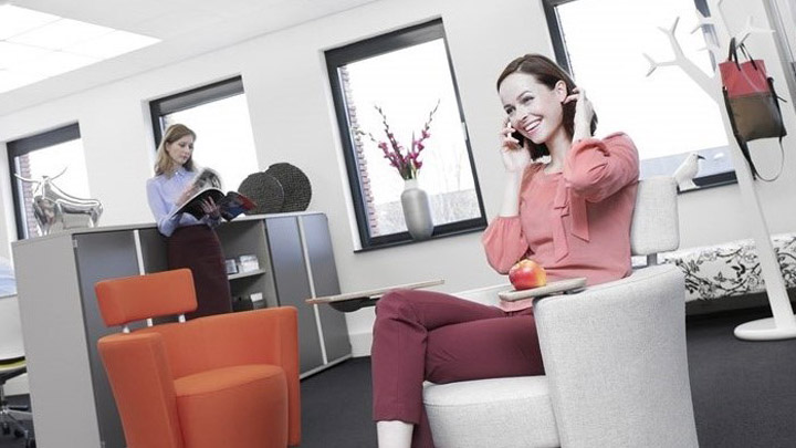 Woman on the phone under Soundlight Comfort solution. Ideal office lighting for more comfortable workplaces.