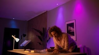 Philips Hue smart LED lights create vibrant purple and pink ambiance in living room, showcasing customizable mood lighting for movie nights and relaxation in modern homes.