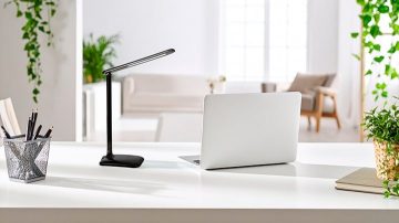 In a bright white room we can see a table lamp and a laptop on a desk