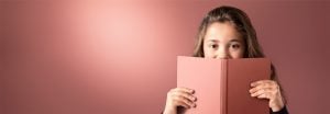 "Young girl peeking over pink book against soft LED-lit background, showcasing warm, even illumination for comfortable reading environments."